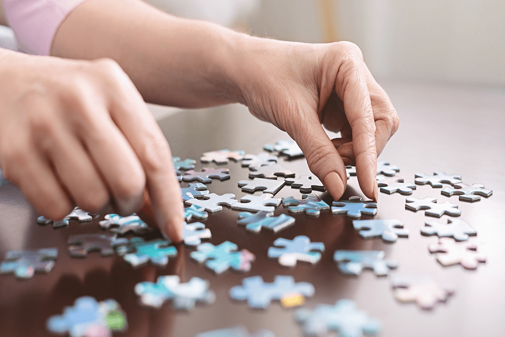 elderly woman's hands putting together jigsaw puzzle