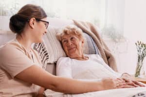 Elderly woman in hospital bed with social services worker helping her