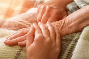 person holding hand of elderly patient in bed